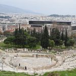 Next to the Odeon of Herodes Atticus, there is a more modest theater: the Theater of Dionysus. The black building behind the trees is the new Acropolis Museum.